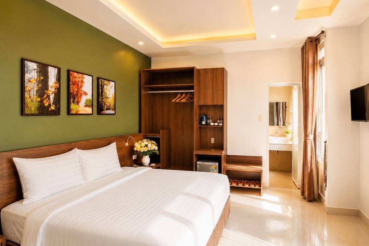 A hotel room with a large bed, a wardrobe, a vanity with a mirror, and a television.