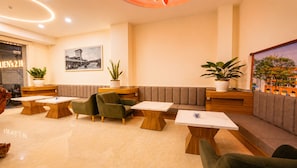 A modern lobby with seating areas, tables, and potted plants.