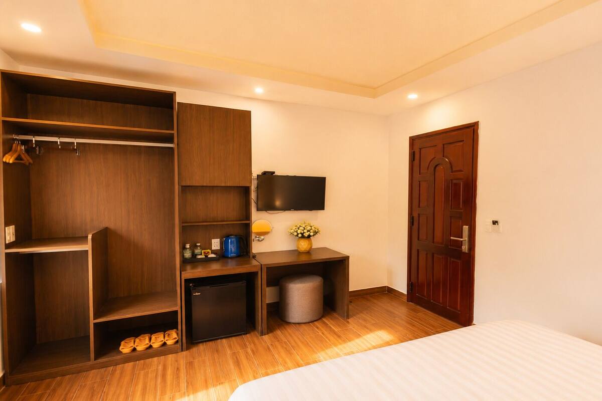 A bedroom with a bed, wardrobe, desk, and a television.