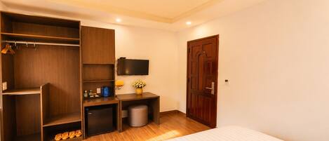 Un dormitorio con cama, armario, escritorio y televisor.