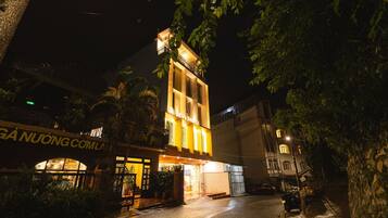 A hotel with a prominent entrance, a balcony, and a sign indicating the name.