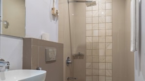 Un baño con inodoro, lavamanos, espejo, ducha y toallero.