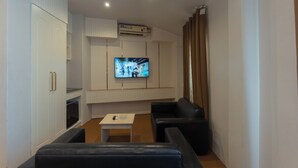 Una sala de estar moderna con un televisor de pantalla plana, un sofá, una mesita y armarios empotrados.