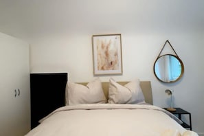Una camera da letto con un letto, un quadro incorniciato, uno specchio rotondo e un armadio nero.