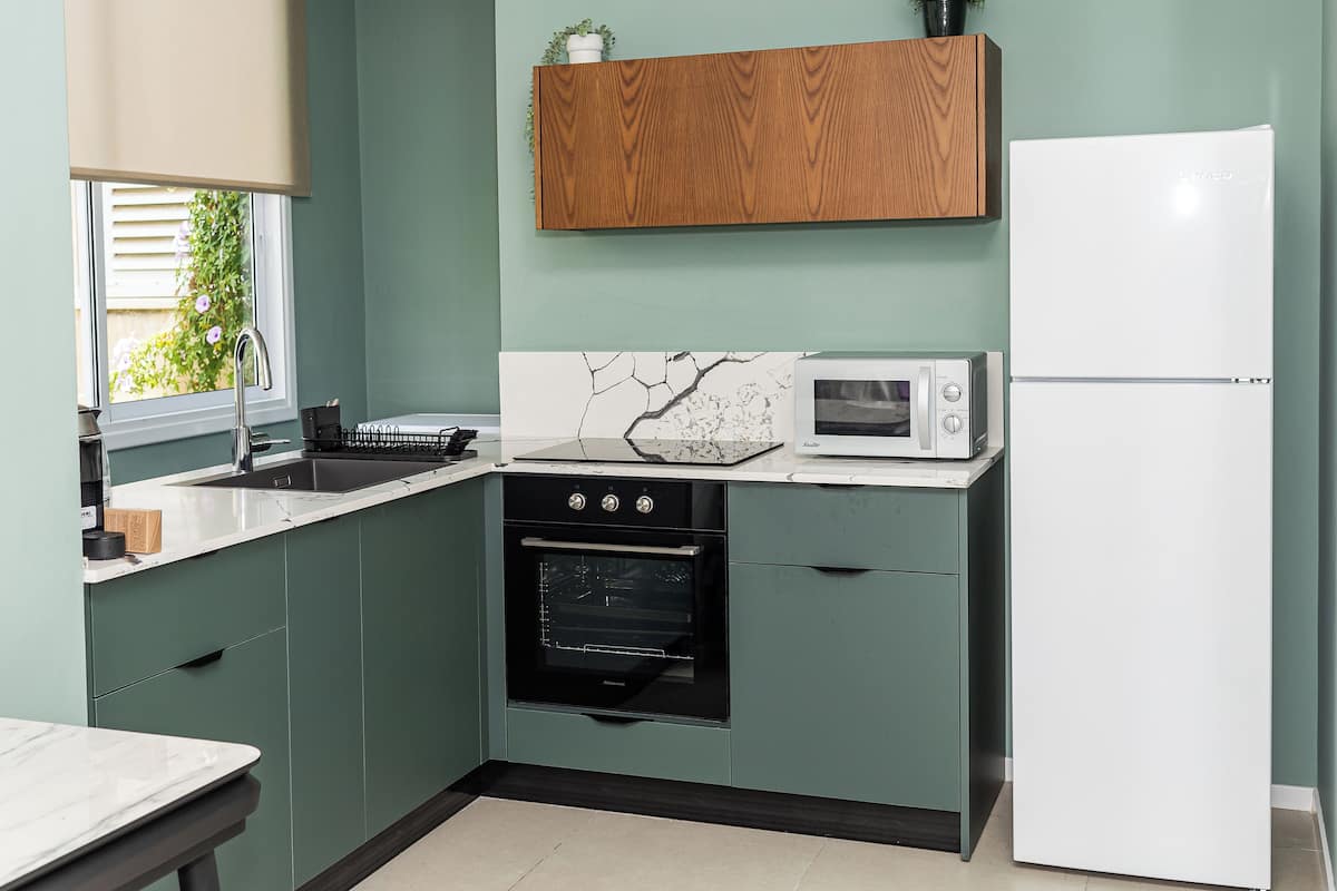 A compact kitchen with a sink, stove, microwave, and refrigerator.