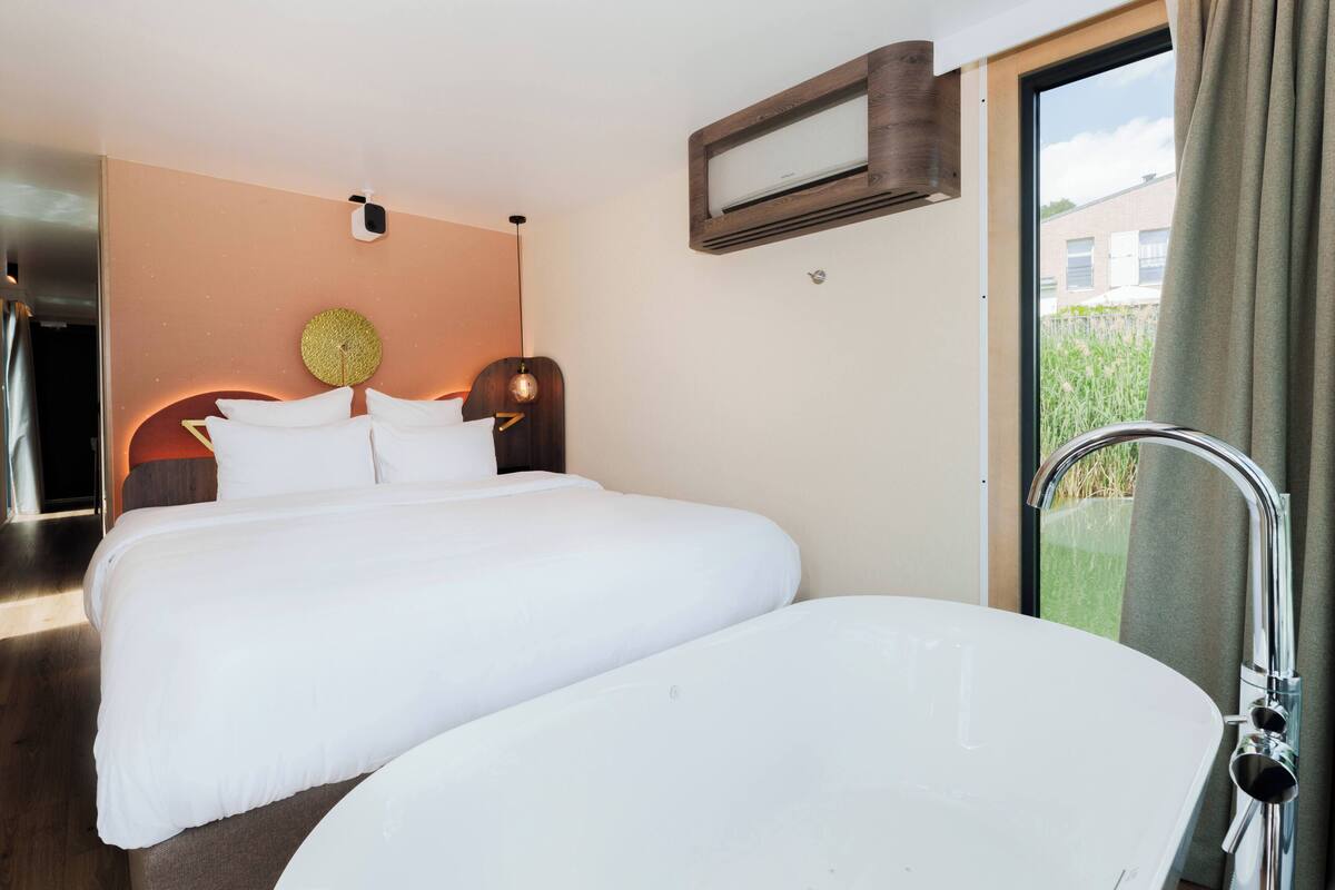 Een hotelkamer met een groot bed, een inloopbad en een raam met uitzicht.