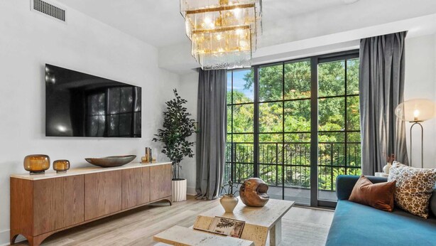 Una sala de estar moderna con un ventanal grande, una mesa consola de madera, un sofá azul y un televisor de pantalla plana montado.