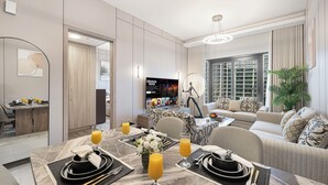 A modern hotel room with a dining area, a sofa set, and a television.