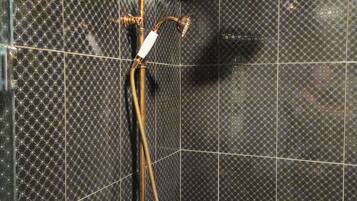Un baño con sistema de ducha, que incluye un cabezal de ducha manual y un grifo instalado en la pared.