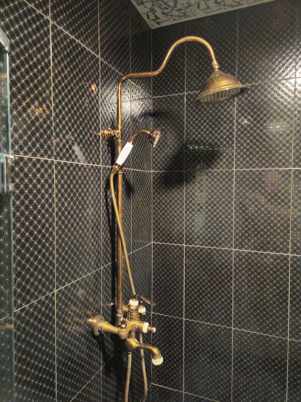 A bathroom with a shower system, including a handheld showerhead and a wall-mounted faucet.
