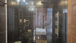Uma casa de banho moderna com chuveiro em cabine de vidro, sanita e lavatório.
