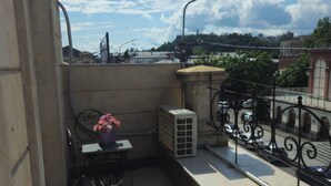Varanda com mesa e cadeiras, um vaso de planta e vista para a paisagem urbana.