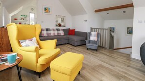 A spacious living room with a high ceiling, a large sofa, a yellow armchair, and a small ottoman. - Coastguard Lookout (Weymouth)