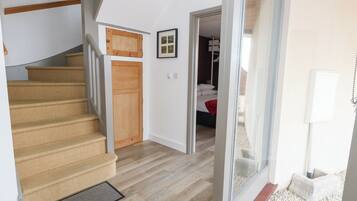 A staircase leading to a bedroom with a wooden door, a framed picture on the wall, and a bed with white bedding.