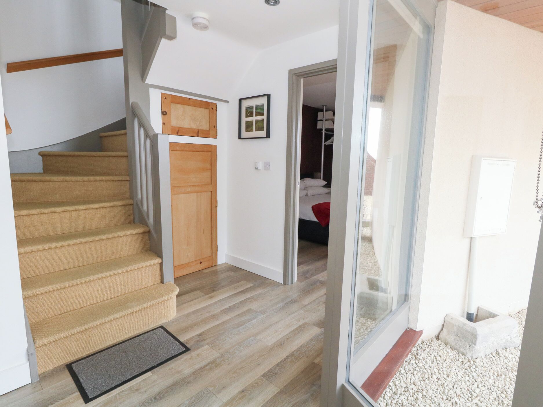 A staircase leading to a bedroom with a wooden door, a framed picture on the wall, and a bed with white bedding.
