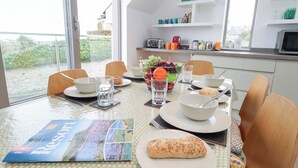 A dining table set with plates, bowls, glasses, and a brochure. - Coastguard Lookout (Weymouth)