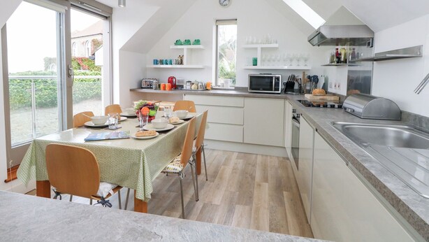 A modern kitchen with a dining area, featuring a large window, a microwave, and a sink. - Coastguard Lookout (Weymouth)