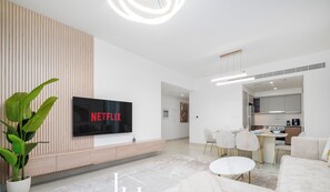 Ein modernes Wohnzimmer mit Flachbildfernseher, einem Essbereich und einer Küche.