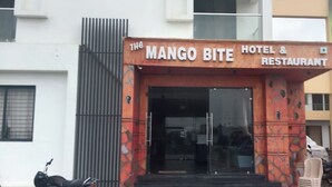 The entrance to 'Mango Bite Hotel & Restaurant' with a glass door and a sign above it. - Mango Bite Hotel & Restaurant (Mandvi)