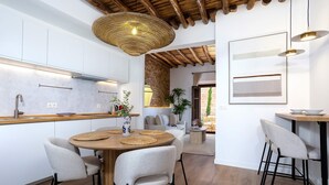 Een moderne keuken met een ronde houten tafel, vier stoelen en een hangende geweven lamp.