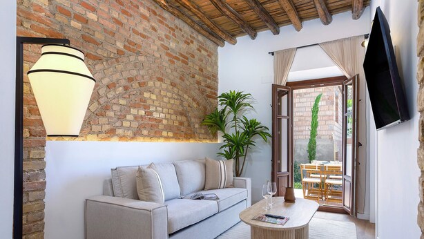 Een gezellige woonkamer met een bakstenen muur, een bank, een salontafel en een aan de muur bevestigde televisie.