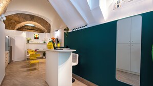 A modern kitchen with a central island, a dining area with yellow chairs, and a green accent wall. - Maison Lulu - Naples Old Town (Naples)