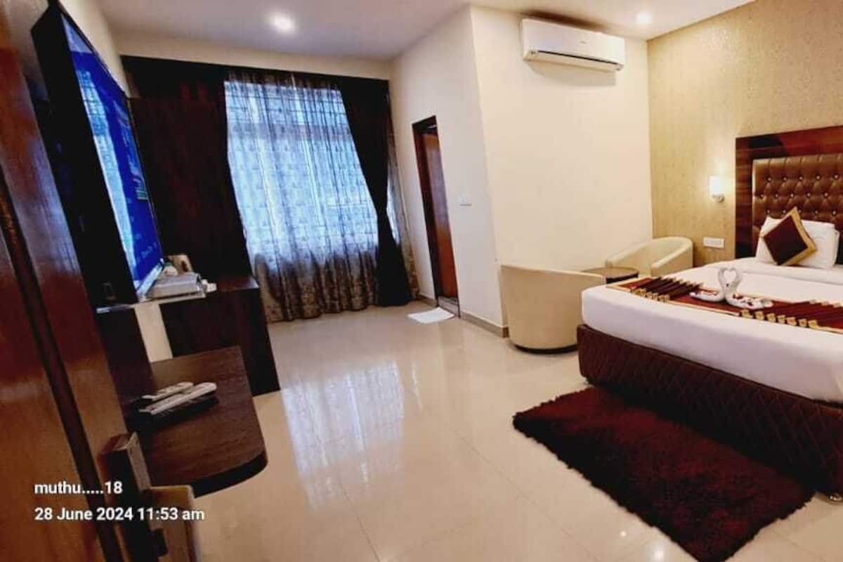 A hotel room with a large bed, a TV, a desk, and a chair.