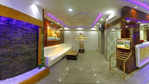 A reception area with a stone wall, a white sofa, a reception desk, and a sign that reads "HOTEL THE PRINCE ROYAL". - Hotel The Prince Royal  (Bengaluru)