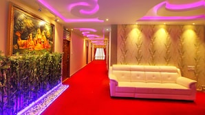 A hotel corridor with a red carpet, a white sofa, a mural, and decorative lighting. - Hotel The Prince Royal  (Bengaluru)