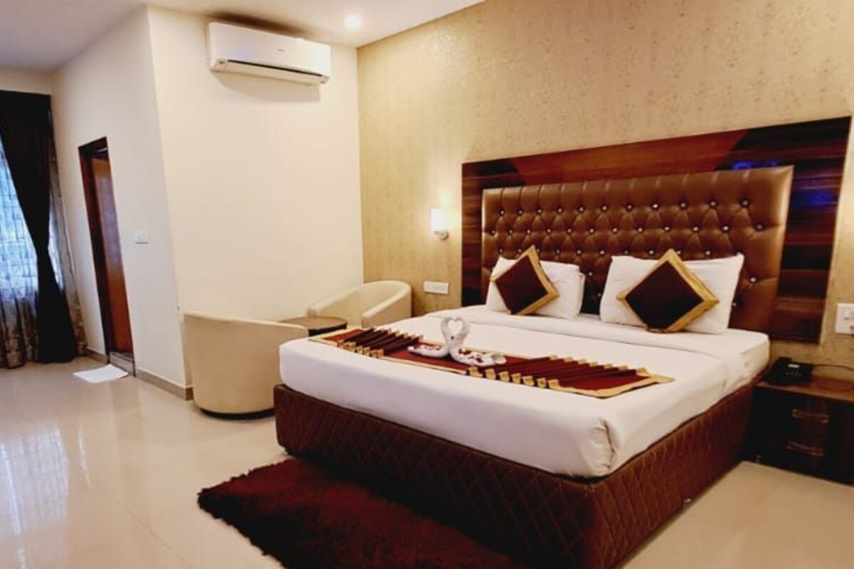 A hotel room with a large bed, a TV, a desk, and a chair.
