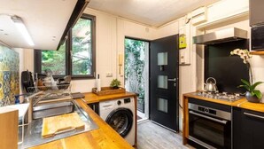 A compact kitchen with a washing machine, a sink, a stove, and a small dining area.