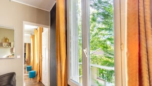 A room with a large window, a door leading to another room, and a visible outdoor view.