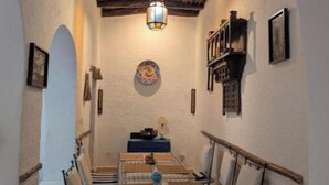 A narrow hallway with a rustic ceiling, a table with chairs, and a lantern. - RIAD MEDINA (Essaouira)