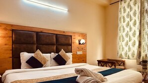 A neatly made bed with a headboard, a bedside table with a lamp, and a window with curtains. - The Kanchanikoot (Manali)