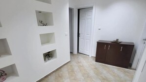 A hallway with tiled flooring, white walls, and a door leading to another room. - Lakeside View Apartment (Udënisht)
