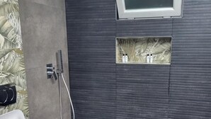 A modern bathroom with a shower, a toilet, and a mounted TV. - Lakeside View Apartment (Udënisht)