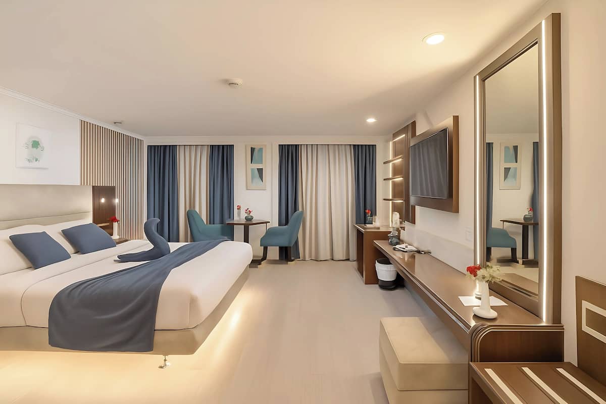 Een moderne hotelkamer met een groot bed, een bureau, een stoel en een grote spiegel.
