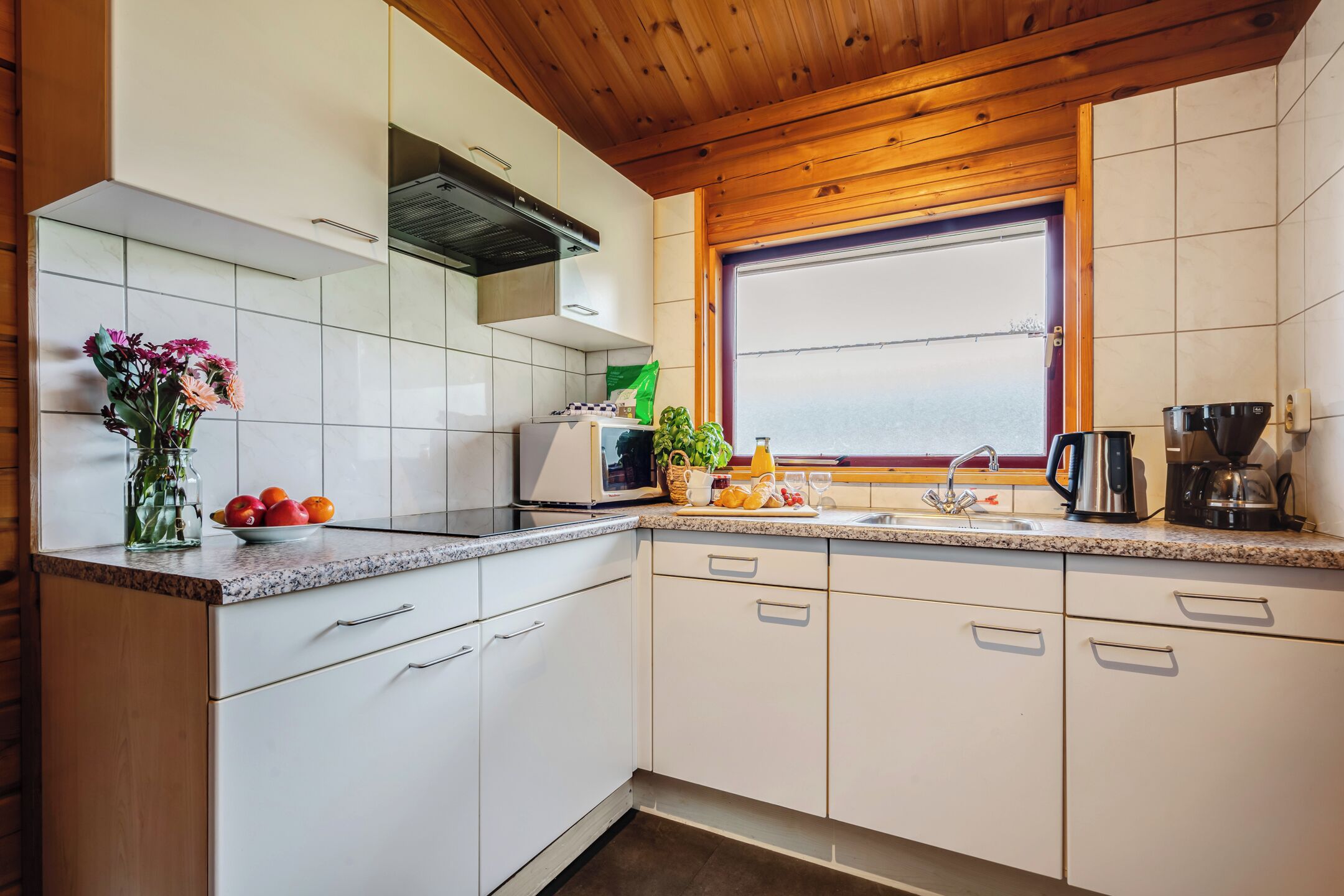 Een koelkast, een kookplaat, een koffiezetapparaat/waterkoker, eettafels