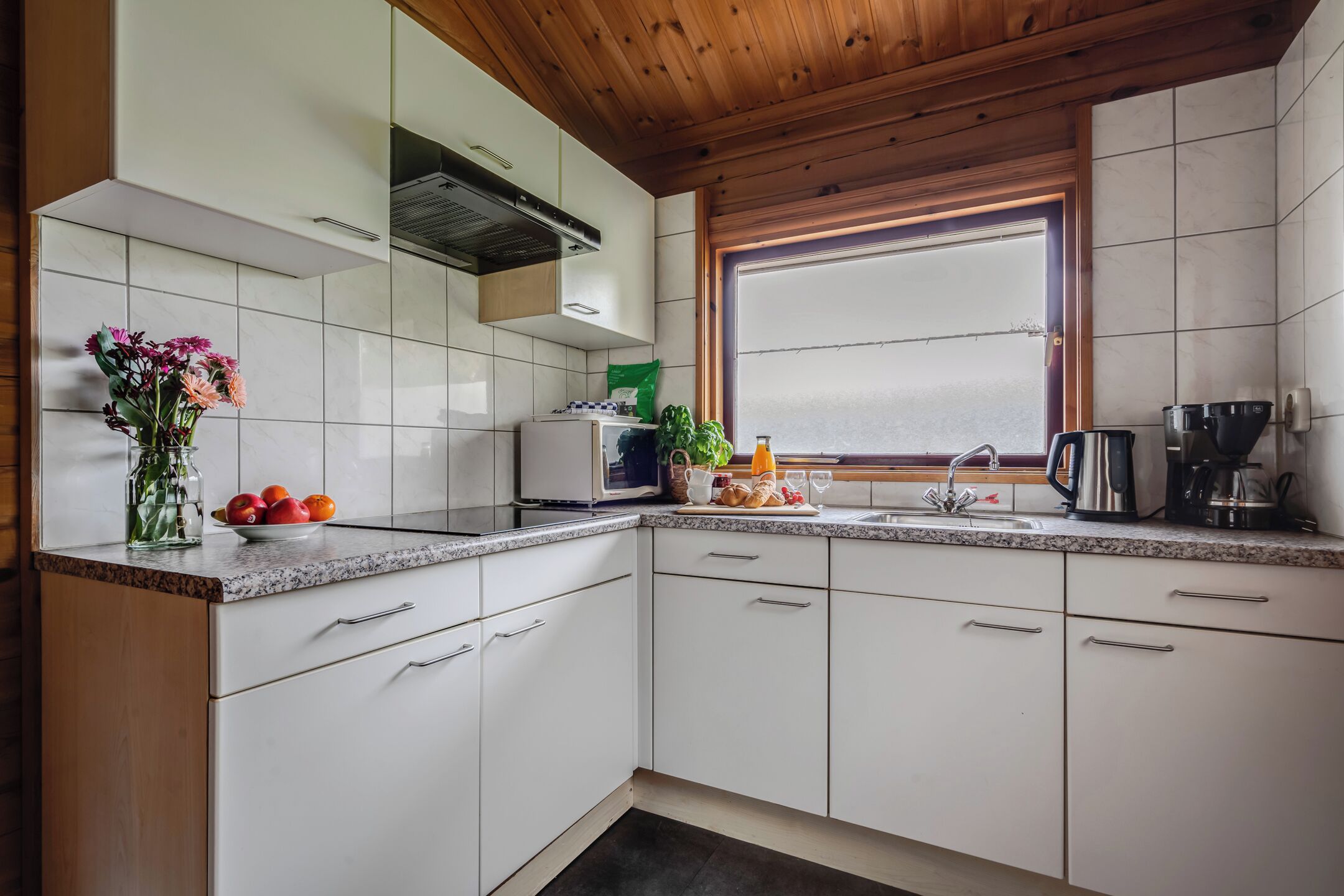 Een koelkast, een kookplaat, een koffiezetapparaat/waterkoker, eettafels