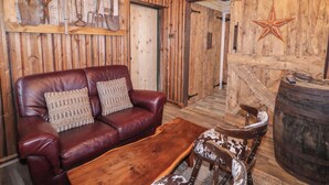 A rustic barn-themed room with a leather sofa, wooden coffee table, and a wooden chair. - Rusty Barn (Limavady)