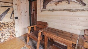 A rustic wooden cabin interior with a bench, a fur coat on the wall, and a door. - Rusty Barn (Limavady)