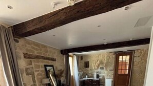 Une chambre à coucher avec un lit, une commode et un bureau. On y trouve un mur en pierre et une poutre en bois au plafond.