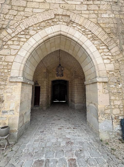 A stone archway leading into a building with a cobblestone floor.