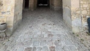 Un arc en pierre mène à un bâtiment dont le sol est pavé de pierres.