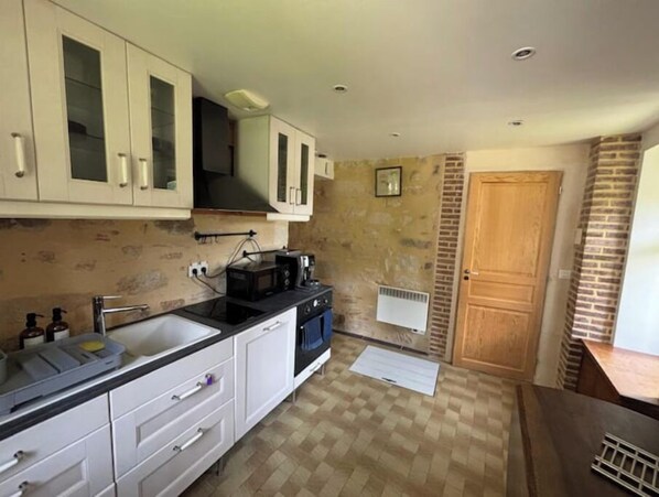 A compact kitchen with white cabinets, a black countertop, and a built-in microwave.