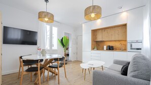 A modern kitchen with wooden cabinets, a built-in oven, and a dining area with a round table and chairs. - Vallecano Apartments by Olala Homes (Madrid)