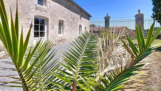 A stone building with arched windows and a stone fence.