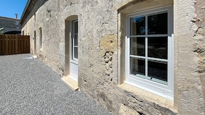 A stone building with arched windows and a gravel driveway.