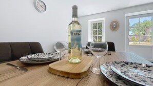 A dining table with a bottle of wine, two wine glasses, and plates.
