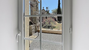 A view through a glass door with a stone structure and a garden.